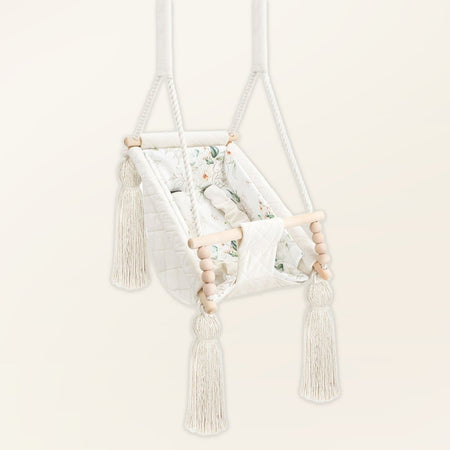 Amaca altalena per bebè in velluto Beige, in velluto, vista di tre quarti con nappe, perle di legno e seduta imbottita
