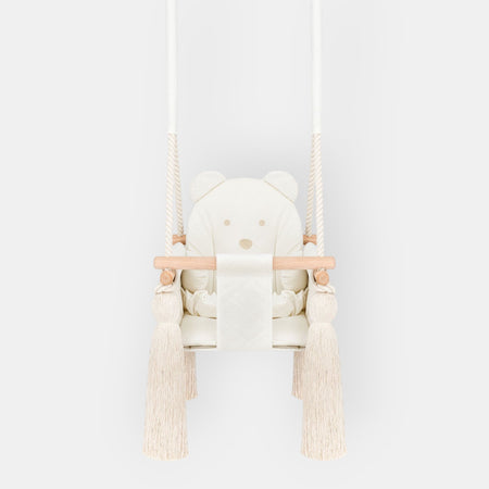 Altalena da interno per bambini in velluto Beige, vista frontale con seduta trapuntata, barra in legno e nappe